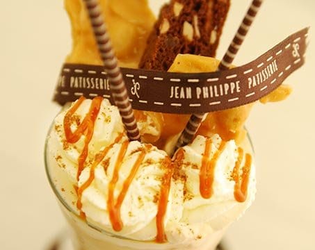 Decadent dessert with whipped cream, caramel drizzle, and Jean Philippe branding | MSC Cruises Decadent dessert with whipped cream, caramel drizzle, and Jean Philippe branding | MSC Cruises