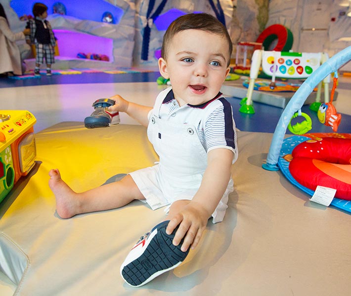 A toddler playing in a colorful onboard kids' play area with toys and activities | MSC Cruises