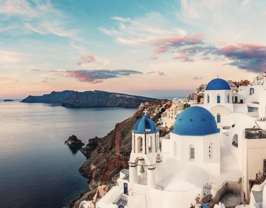 Sunset over the charming Greek island of Oia, with whitewashed buildings and blue domes. Sunset over the charming Greek island of Oia, with whitewashed buildings and blue domes.